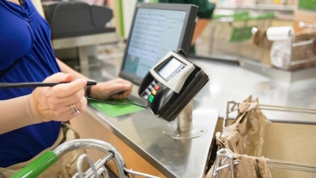 Charity Checkout Campaigns Image of Cashier and Someone Paying at a checkout