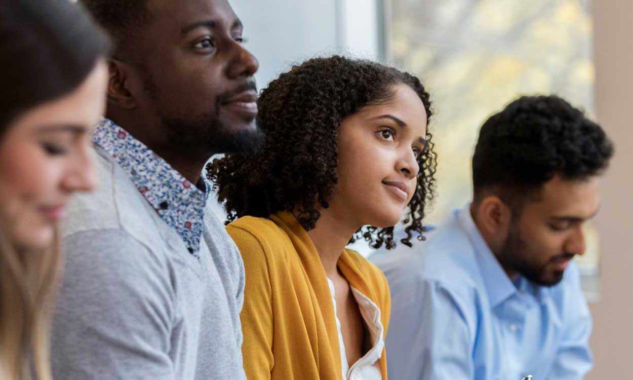 Foundation List Nonprofit Job Postings Site Image of four candidates waiting to meet with an interviewer. A women and man are seen happy, sitting and dressed to impress