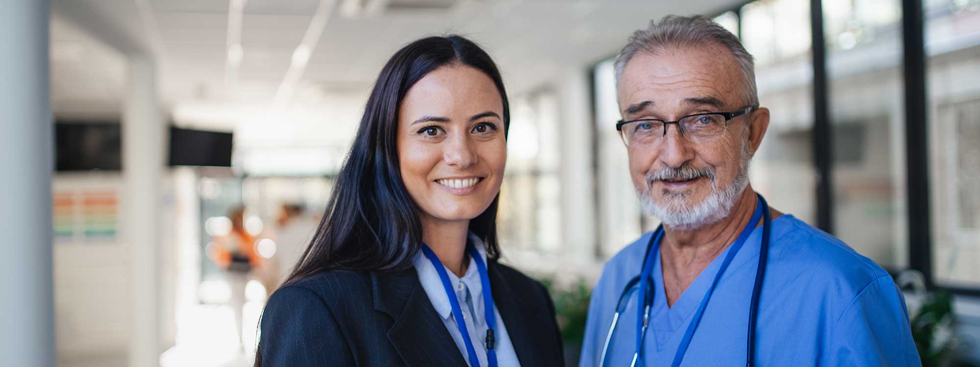 A doctor and a hospital administrator stand in the hospital hallway