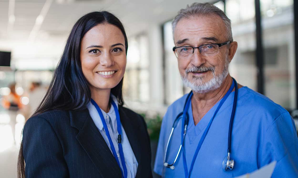 A doctor and a hospital administrator stand in the hospital hallway