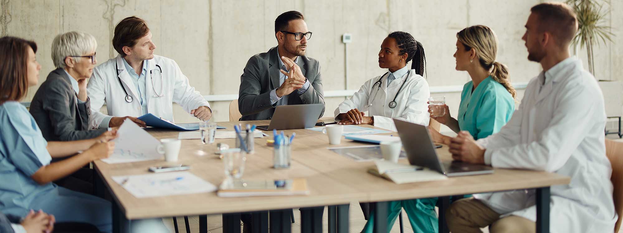 A group of medical professionals sits at a table discussing who to hire to add to their healthcare team