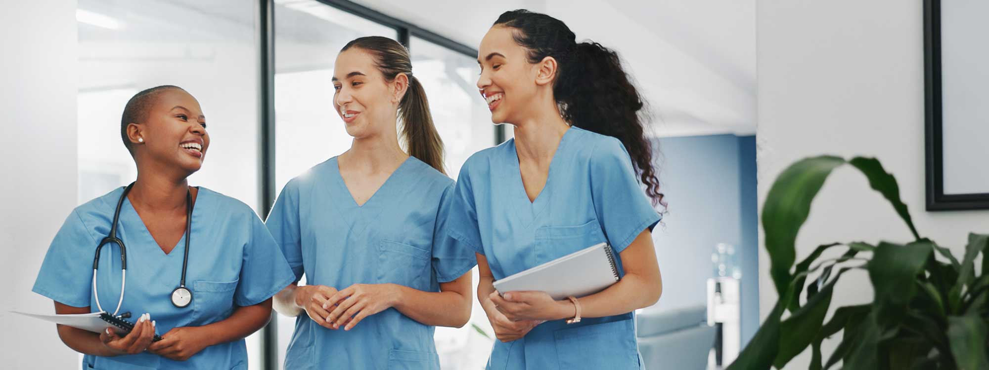 A doctor laughs with her nurses as they walk down the hallways of their healthcare facility