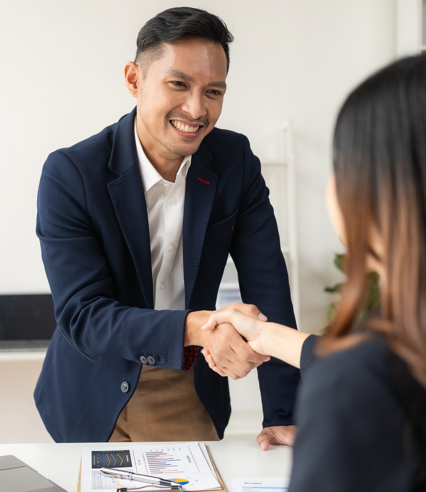 Nonprofit Job Board Candidate is welcomed in an interview he si wearing a blue suit and shaking hands to get a nonprofit job.