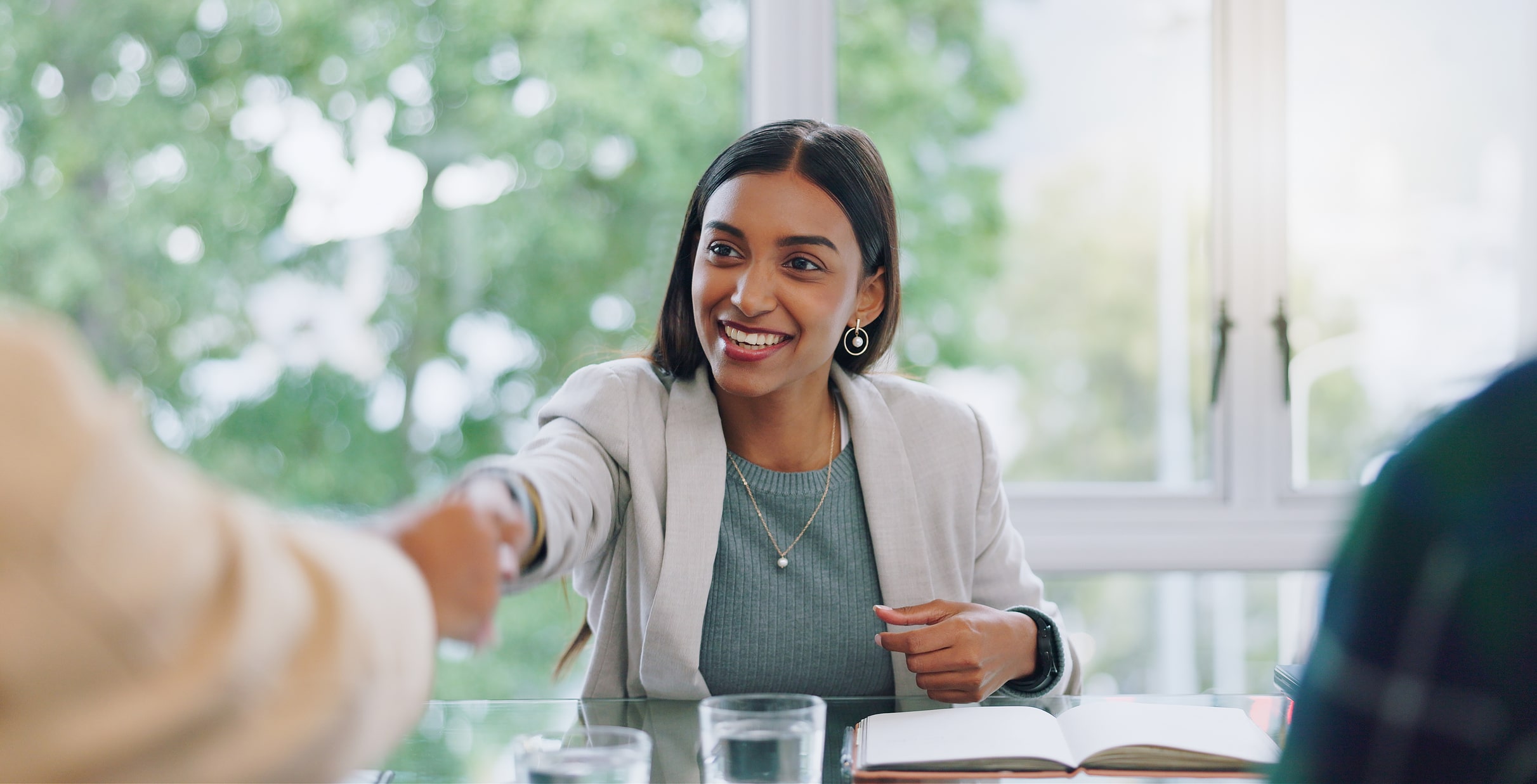 Nonprofit Job Board candidate is shaking hands at an interview after applying for nonprofit jobs wearing a white suit and smiling at a meeting
